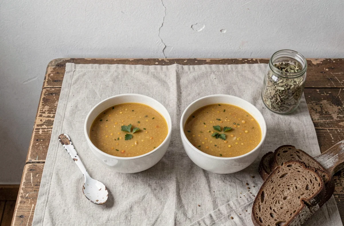 Deux bols de soupe maison et pain complet sur une table simple, illustration d'un repas sain et économique